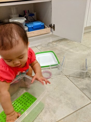 toddler playing with container for fine motor